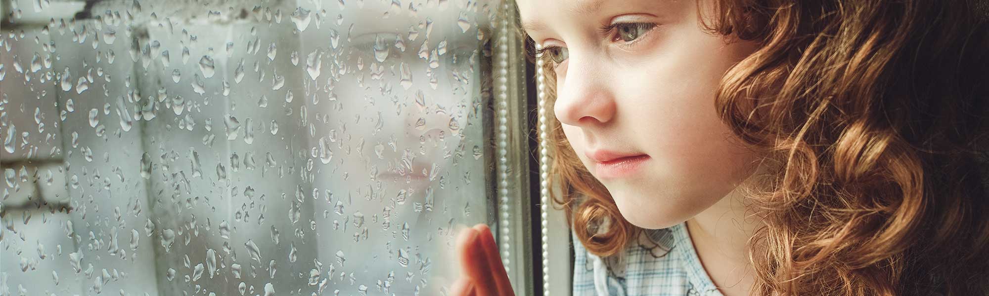 sad child looking out window
